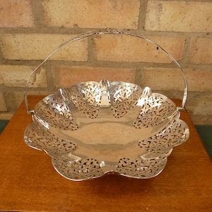 May include: A silver-plated, openwork basket with a handle. The basket has a scalloped edge and a delicate floral design.