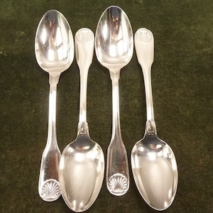 May include: Four silver spoons with ornate handles. Each spoon has a shell design on the handle.