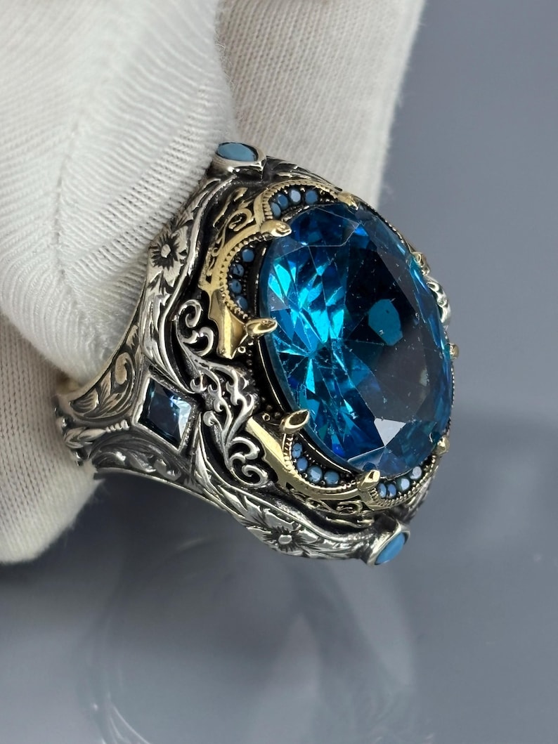 Gloved side-angle close-up showing intricate scroll engravings and the aquamarine stone in a Turkish handmade 925 sterling silver band.