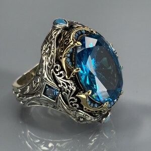Product side/three-quarter shot on gray background highlighting the ring’s depth, engravings, and aquamarine stone profile.