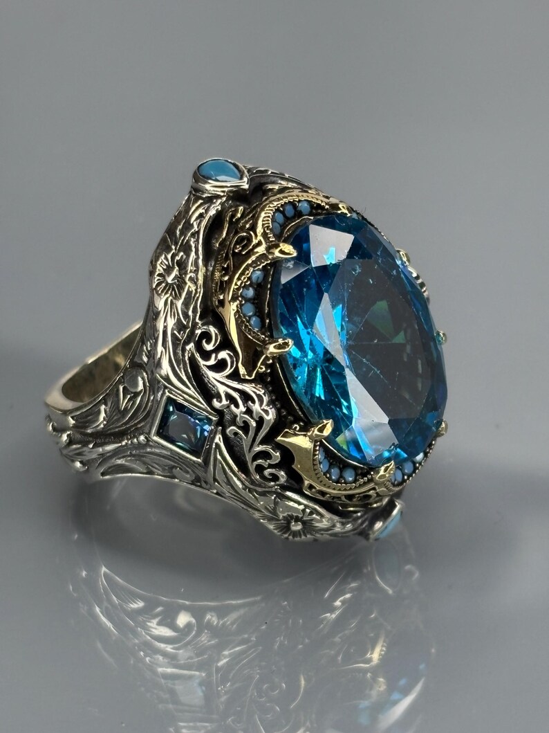 Product side/three-quarter shot on gray background highlighting the ring’s depth, engravings, and aquamarine stone profile.