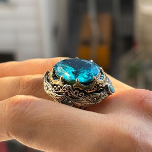 On-hand close-up of 925 sterling silver Turkish handmade men’s ring with oval aquamarine blue stone and vintage Ottoman engraved setting.