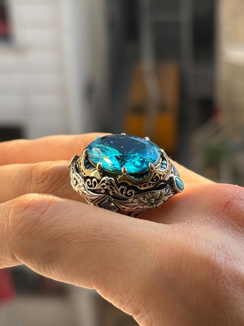 On-hand close-up of 925 sterling silver Turkish handmade men’s ring with oval aquamarine blue stone and vintage Ottoman engraved setting.