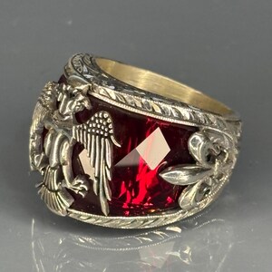 Detailed close-up showing one side of the ring, where the eagle carving is clearly visible. The craftsmanship of the 925 silver band, combined with the rich red stone, emphasizes the power and historic symbolism of the piece. Perfect angle to showcase artisan quality.