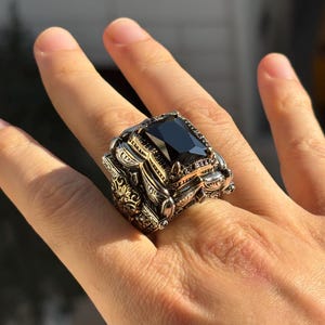 Side/top close-up on hand highlighting the layered Ottoman-style frame and chunky profile around the black onyx stone.
