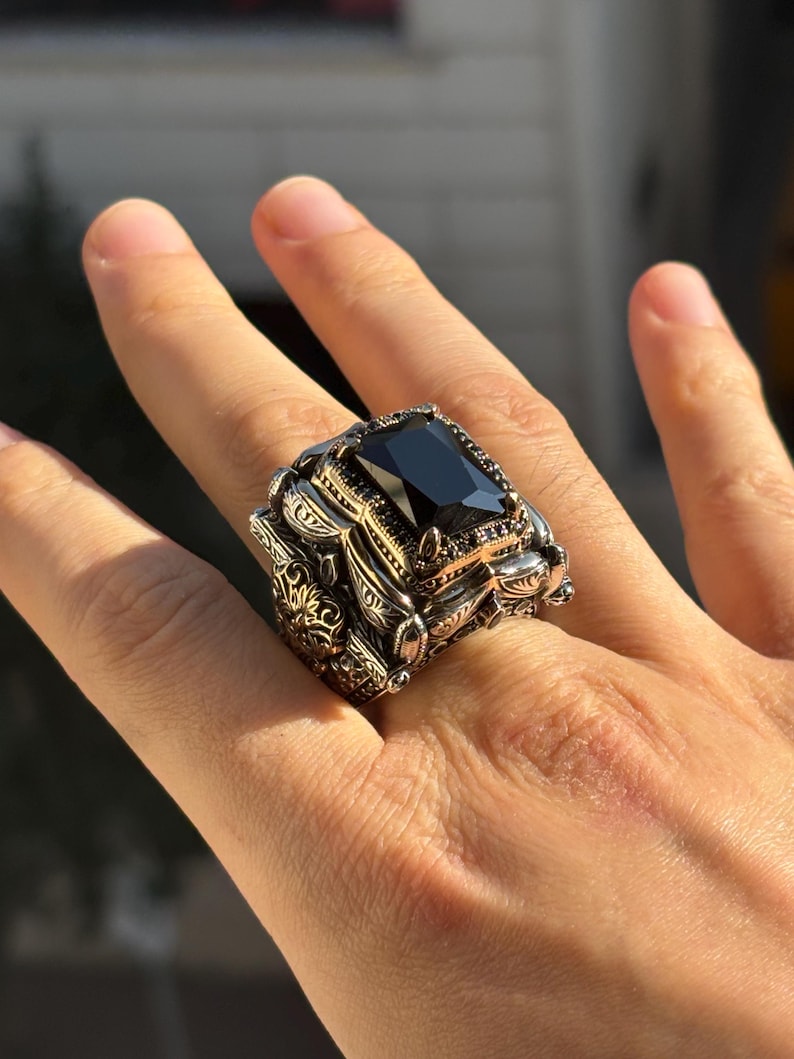 Side/top close-up on hand highlighting the layered Ottoman-style frame and chunky profile around the black onyx stone.