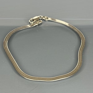 May include: A silver snake chain bracelet with a clasp closure.