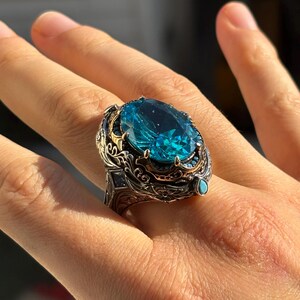 On-hand angled close-up highlighting the raised aquamarine stone, ornate bezel, and detailed Turkish silverwork.
