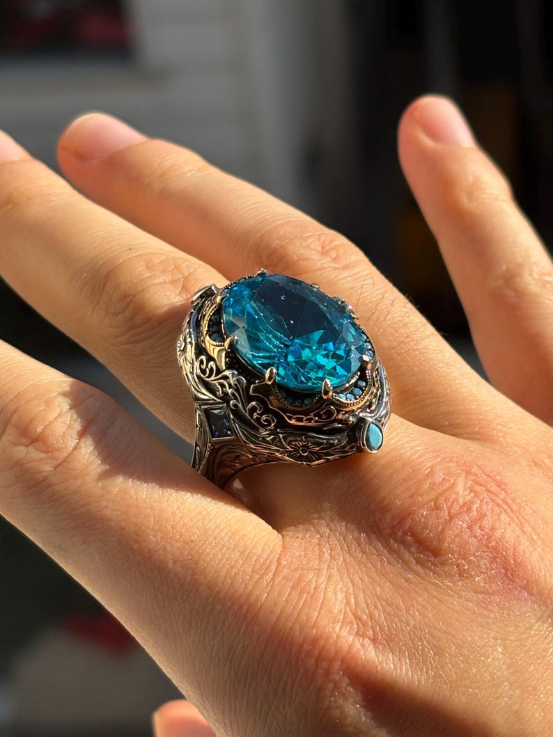 On-hand angled close-up highlighting the raised aquamarine stone, ornate bezel, and detailed Turkish silverwork.