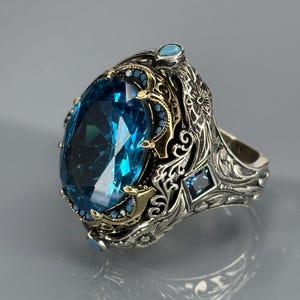 Product three-quarter view on gray background of the 925 sterling silver men’s ring with bright aquamarine blue stone and vintage detailing.