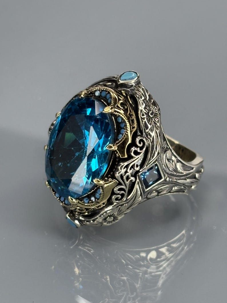 Product three-quarter view on gray background of the 925 sterling silver men’s ring with bright aquamarine blue stone and vintage detailing.