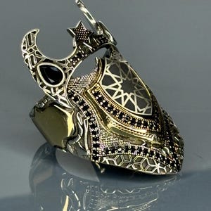 May include: A silver ring with a black stone and intricate geometric designs. The ring features a crescent moon and star motif.