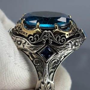 Gloved back/side view showing the band’s Ottoman-inspired scrollwork and sturdy 925 sterling silver construction beneath the aquamarine setting.