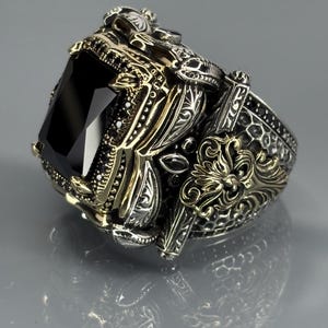Gloved angled close-up highlighting the side engravings, antique finish, and elevated black onyx setting.