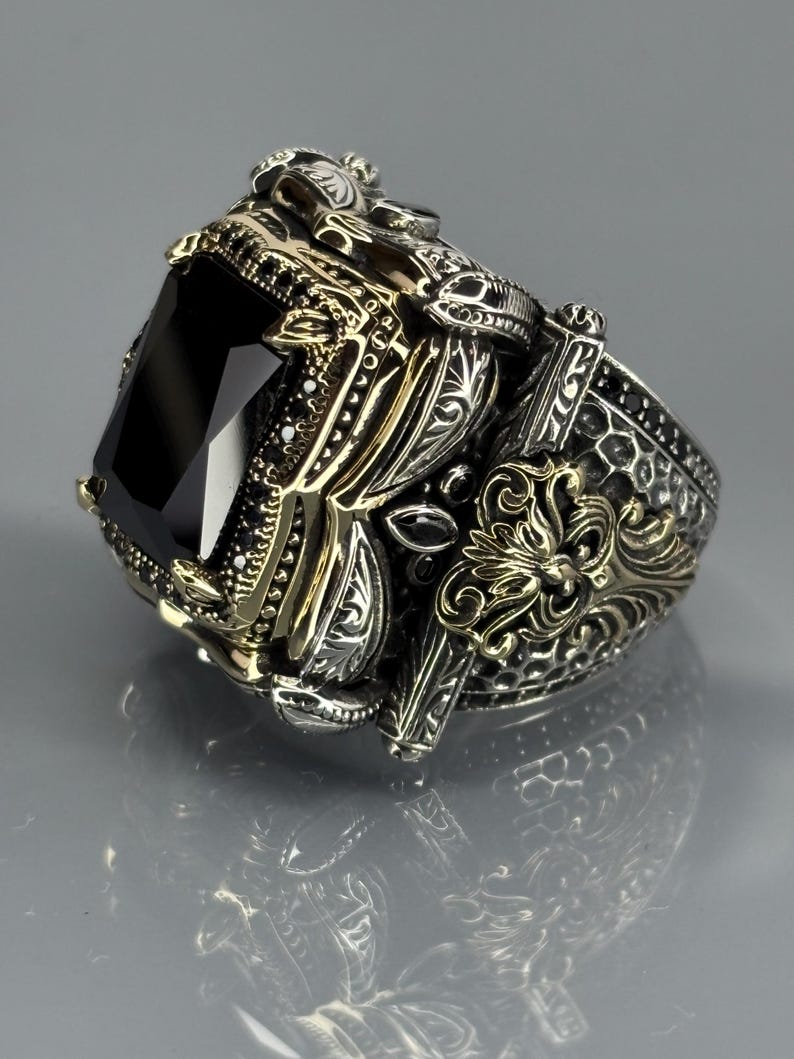 Gloved angled close-up highlighting the side engravings, antique finish, and elevated black onyx setting.