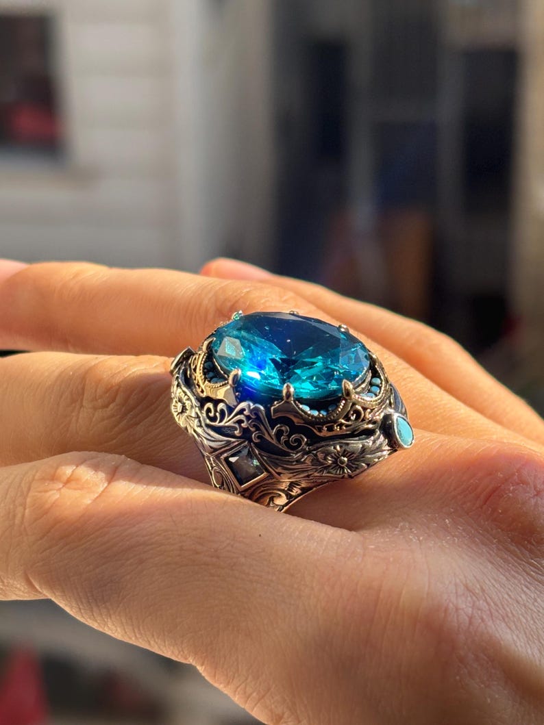 On-hand close-up focusing on the aquamarine stone’s blue shine and the ring’s layered, engraved top design.