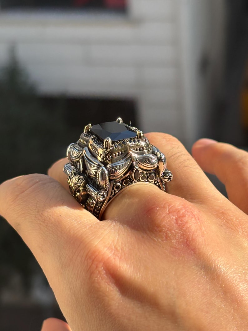 On-hand three-quarter view showing the bold square black onyx centerpiece and engraved shoulders of the Turkish silver ring.
