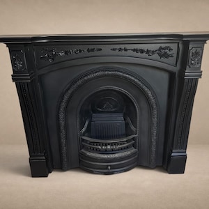 May include: A matte black cast iron fireplace surround featuring an arched opening, a central grate, and decorative floral relief carvings along the mantelpiece and side pillars. The structure has a wide top shelf and a curved base design.