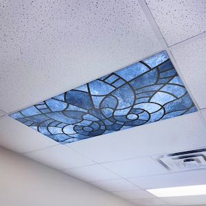 May include: A blue and black stained glass ceiling tile with a geometric pattern. The tile is designed to look like a traditional stained glass window.