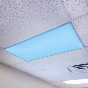 May include: A rectangular, illuminated ceiling light fixture with a soft blue glow. The light is recessed into a white, textured ceiling, surrounded by a thin, silver frame. The ceiling tiles are square and have a speckled pattern.