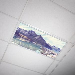 May include: A ceiling light fixture with a printed image of a mountain range and a lake with a wooden pier. The image is in a vintage style with faded colors.