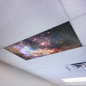 May include: A ceiling tile with a printed image of a nebula with stars. The tile is white and the image is in shades of pink, orange, and blue.