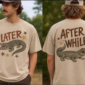 May include: Beige t-shirt with a front and back design. The front features the word "LATER" above a detailed alligator illustration, with stars. The back says "AFTER WHILE" with a similar alligator design.