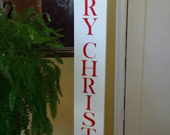 Puede incluir: Un letrero de madera blanco con las palabras "Merry Christmas" en letras rojas.