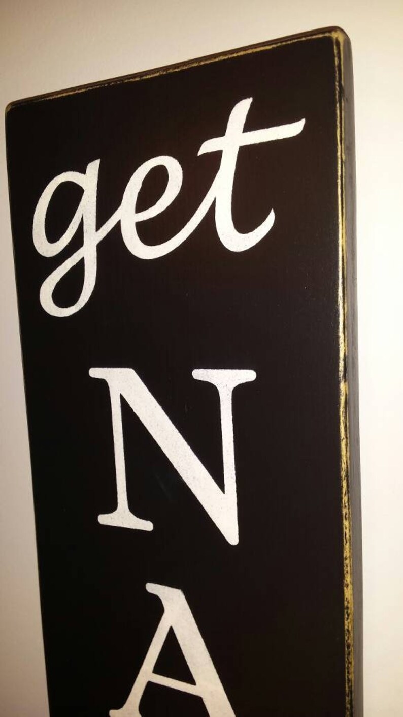 May include: Black wooden sign with white painted text that reads "get N A".