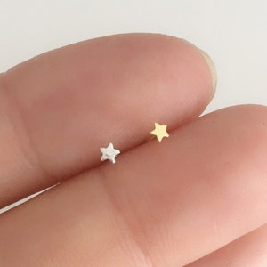 Puede incluir: Se muestran dos peque&ntilde;os pendientes en forma de estrella, uno plateado y otro dorado. Los pendientes tienen un dise&ntilde;o minimalista. Probablemente est&aacute;n hechos de metal y son adecuados para el uso diario.