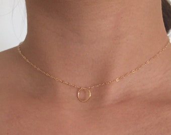 May include: A delicate gold chain necklace with a small circle pendant.