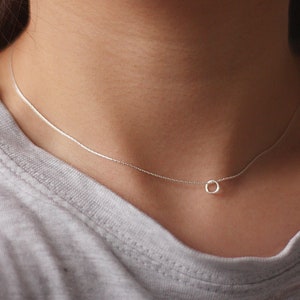 Könnte beinhalten: Eine silberne Kettenkette mit einem kleinen, runden Anhänger.