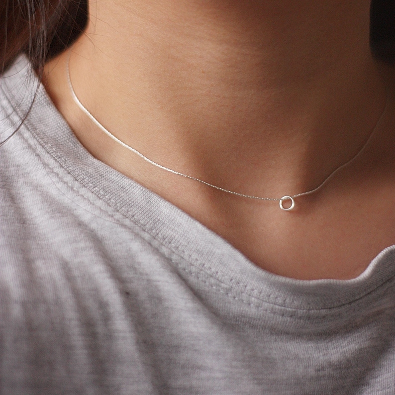 May include: A silver chain necklace with a small, round pendant.