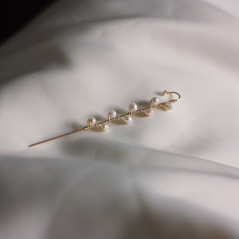 Puede incluir: Delicado pasador de pelo dorado con dise&ntilde;o de ramita. El pasador est&aacute; adornado con peque&ntilde;as perlas irregulares. Tiene un pasador largo y recto para la inserci&oacute;n y un gancho curvado en la parte superior. El fondo es de tela blanca suave.