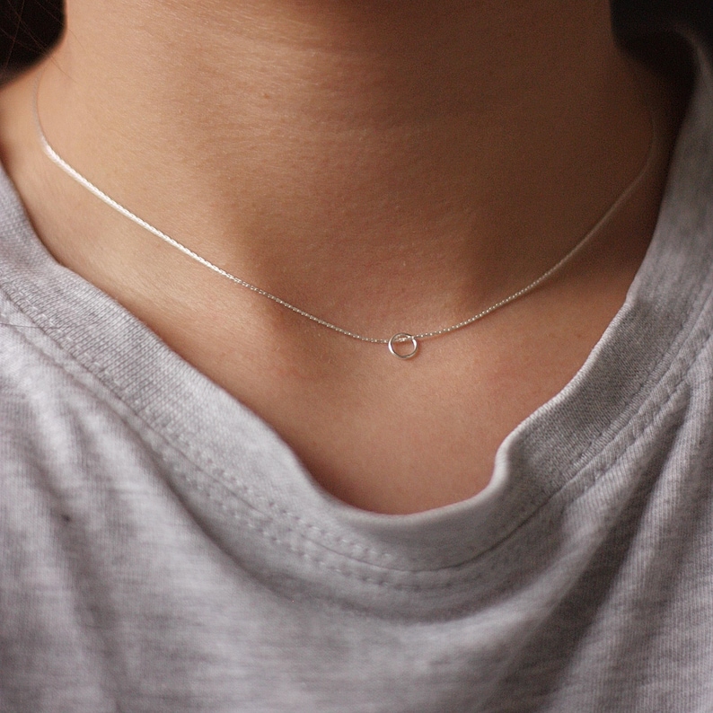 May include: A delicate silver chain necklace with a small circle pendant.