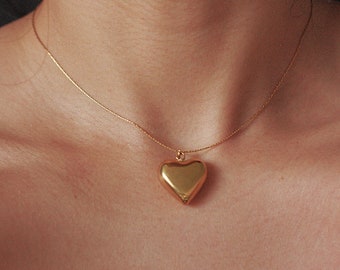 May include: A gold chain necklace with a large, heart-shaped pendant.