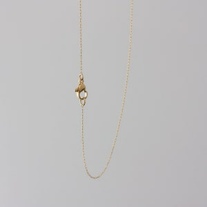 May include: A gold chain necklace with a lobster clasp closure.