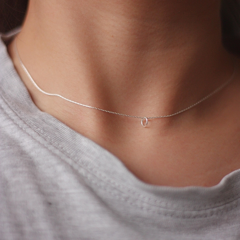 May include: A delicate silver chain necklace with a small, simple circle pendant.