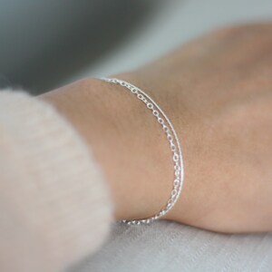 May include: A delicate silver chain bracelet with two different chain styles layered together.
