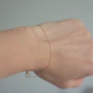 May include: A delicate gold chain bracelet on a person's wrist.