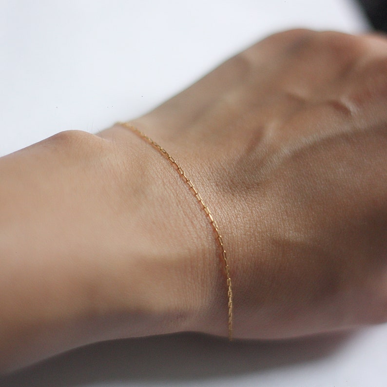May include: A delicate gold chain bracelet on a wrist.