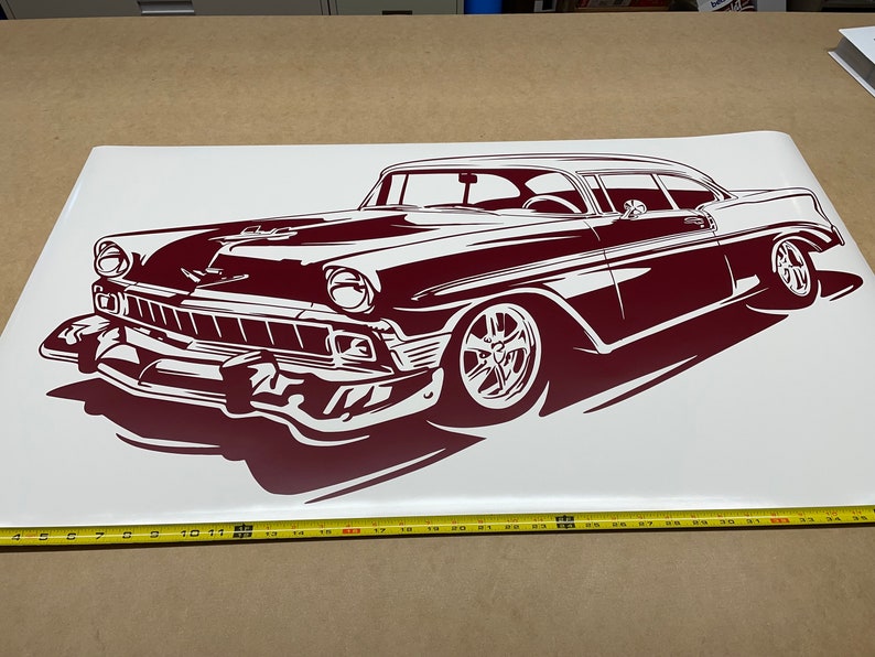 May include: A maroon silhouette of a classic car, a 1950s Chevrolet, on a white background. The car is facing the left side of the image and is in a low angle perspective. The car has a detailed front grill and large wheels.
