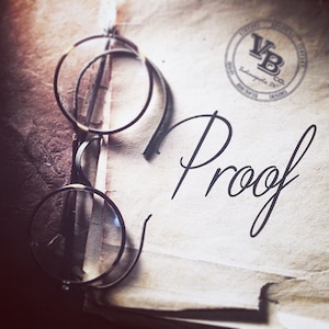 May include: A close-up of a vintage-looking document with the word "Proof" written in cursive. A pair of round eyeglasses with a brown frame are resting on the document. A circular stamp with the text "VB Co. " is visible in the upper right corner.