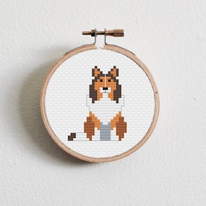 May include: A cross-stitch pattern of a brown and white dog with a gray background, framed in a wooden hoop.