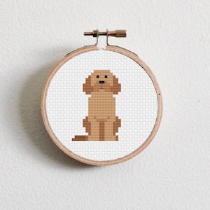 Peut inclure: Un motif de point de croix de chien pixelisé brun dans un cerceau de broderie en bois.