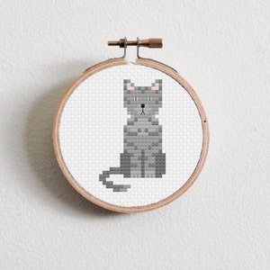May include: A gray cat cross-stitch pattern in a wooden embroidery hoop.