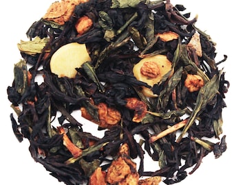 May include: A close-up of a blend of black and green tea leaves with dried apple pieces and small, round, light yellow pieces of candy.