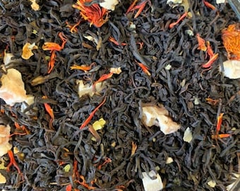 May include: A close-up of a jar filled with loose leaf black tea blend. The tea blend includes dried orange peel, safflower petals, and other dried fruit pieces.