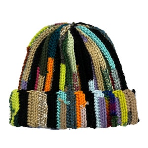 May include: A colorful crocheted beanie hat with a black base and stripes of various colors, including green, blue, orange, and yellow.