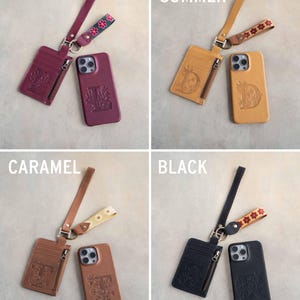 May include: Four leather phone cases and matching cardholders in Sangria, Indian Summer, Caramel, and Black. Each set includes a phone case, cardholder with a zipper, and a wrist strap with decorative floral accents. The phone cases and cardholders feature embossed designs.